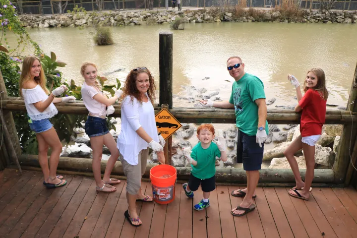 family smiling in front of alligator exhibit